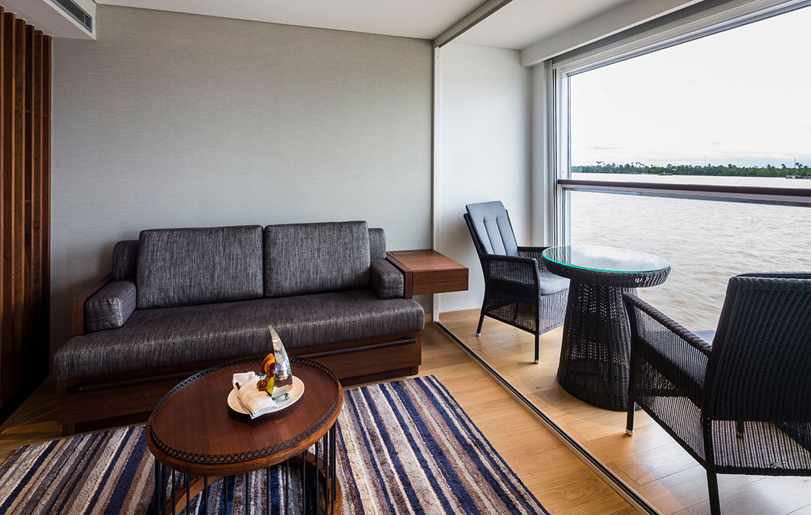 The Scenic Sun Lounge area in the Deluxe Suite on the Scenic Spirit ship, offering views of the Mekong River through a large window.