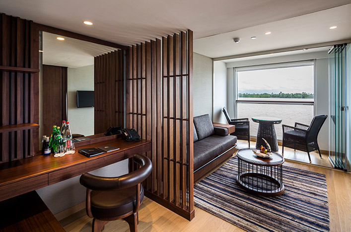 A desk and lounge area in the Grand Deluxe Suite on the Scenic Spirit ship, with a large Scenic Sun Lounge offering river views.