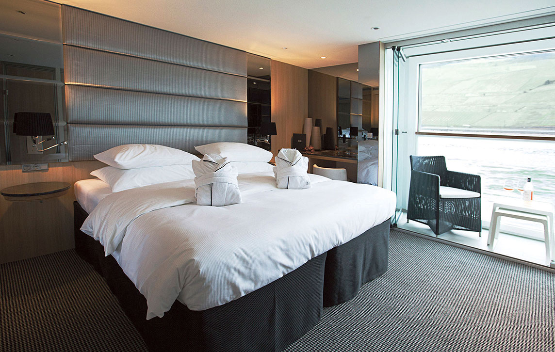 A Queen bed and Scenic Sun Lounge area in a Deluxe Balcony Suite on the Scenic Jasper ship