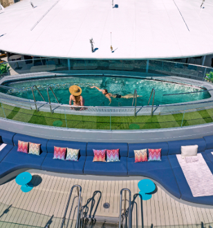 A serene pool on a cruise ship, featuring a vibrant blue lounge chair beside the water, inviting relaxation and leisure.