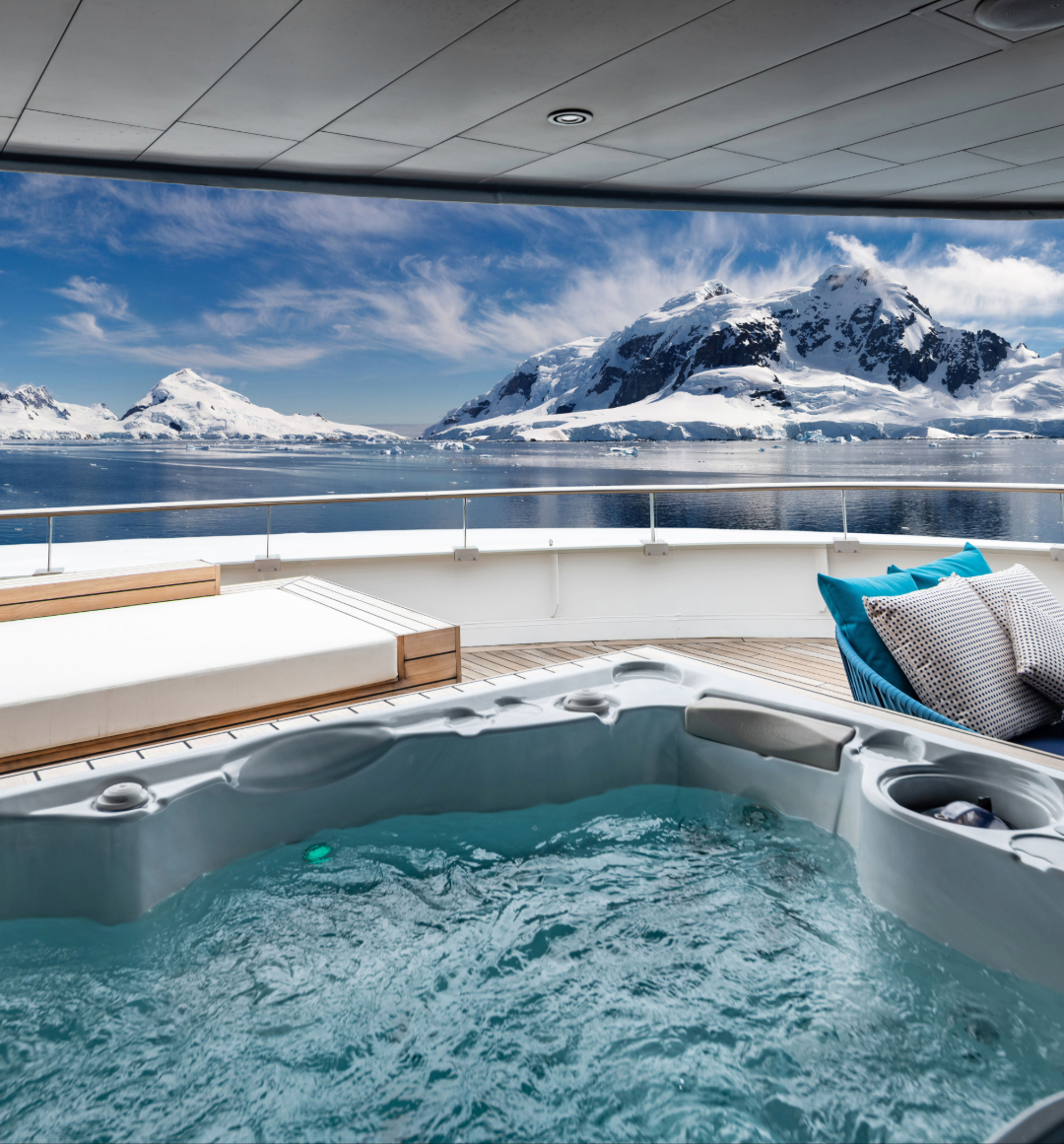 Guest suite deck with hot tub in front of mountainous antarctica background